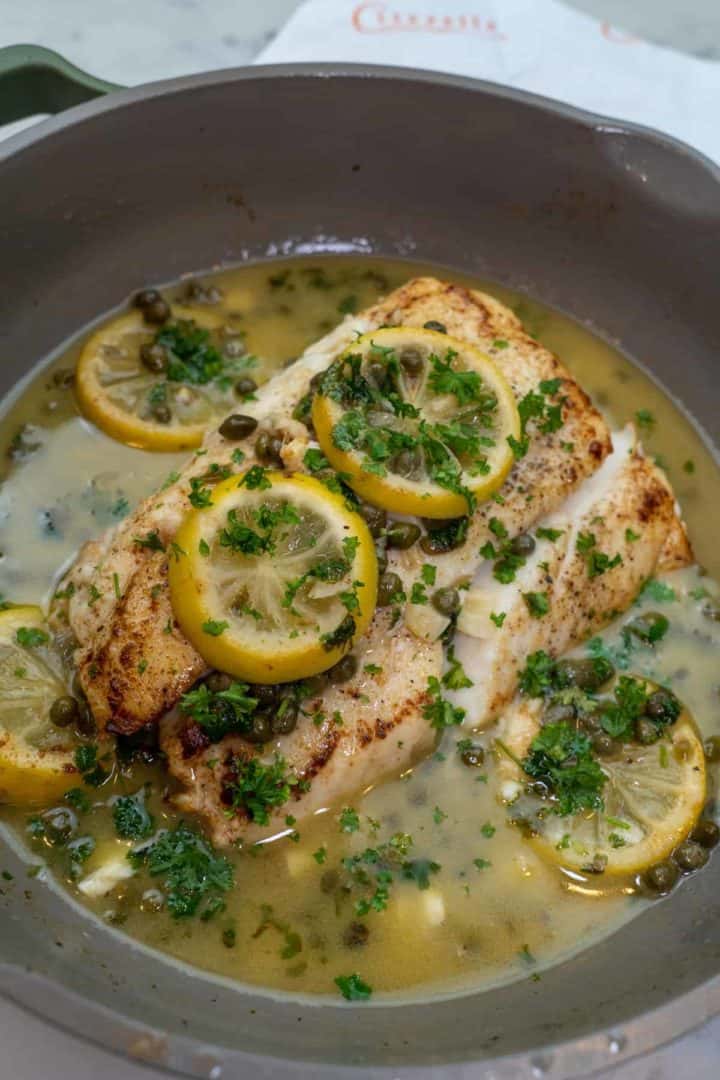 This Pan Seared Halibut Recipe is made with halibut, butter, olive oil, lemons, garlic, white wine, capers and garnished with fresh parsley.