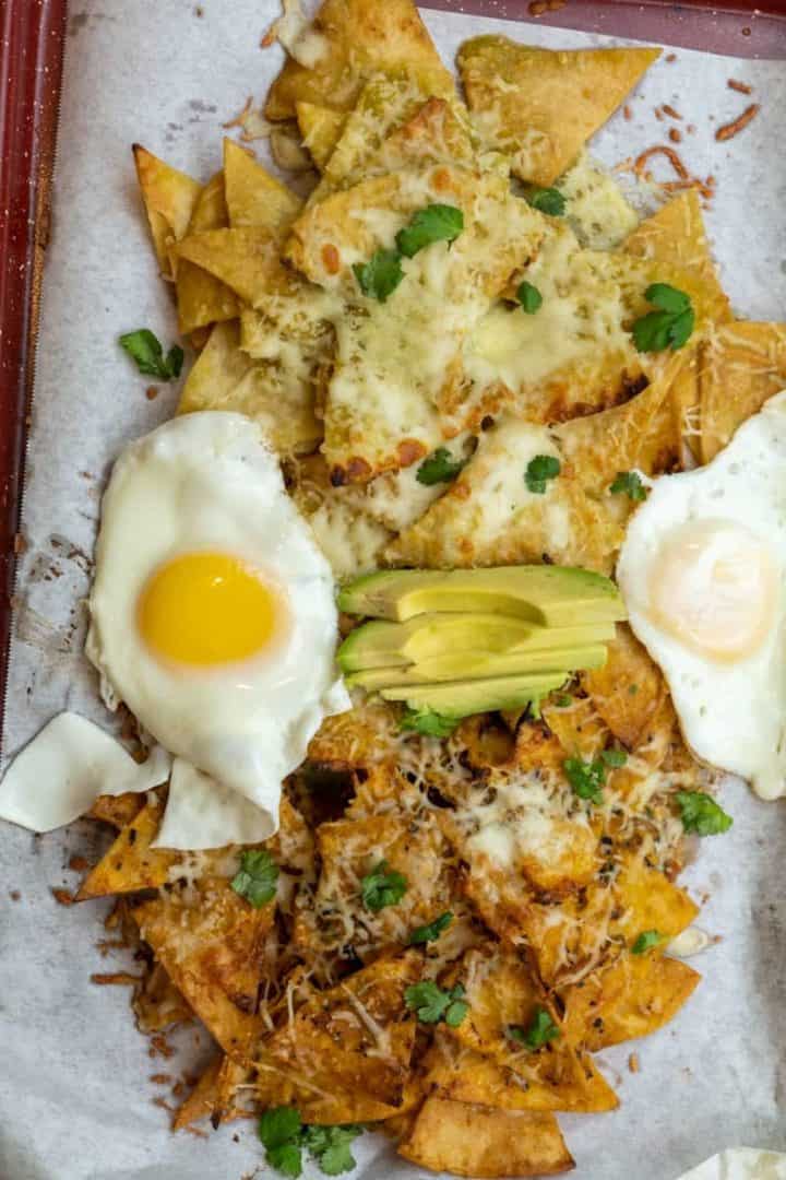 This is an Authentic Chilaquiles Recipe with eggs, avocado, cilantro, queso fresco, and Salsa Verde and Salsa Roja and baked to perfection.