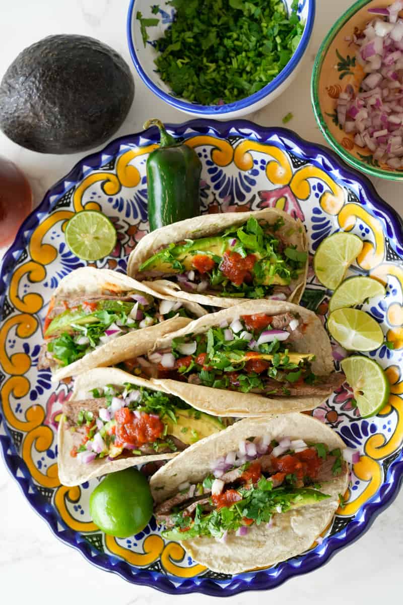 These Carne Asada Tacos Recipe is made with marinated skirt of flank or skirt steak, served on a tortilla and topped with onion and cilantro.