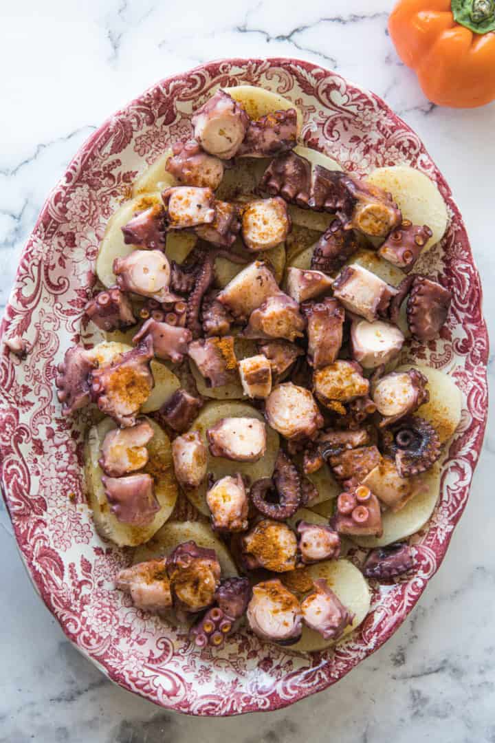 This Spanish Octopus Recipe (Pulpo a la Gallega) is made with boiled potatoes, cooked octopus, olive oil, pimentón, and salt and arranged on a large platter.
