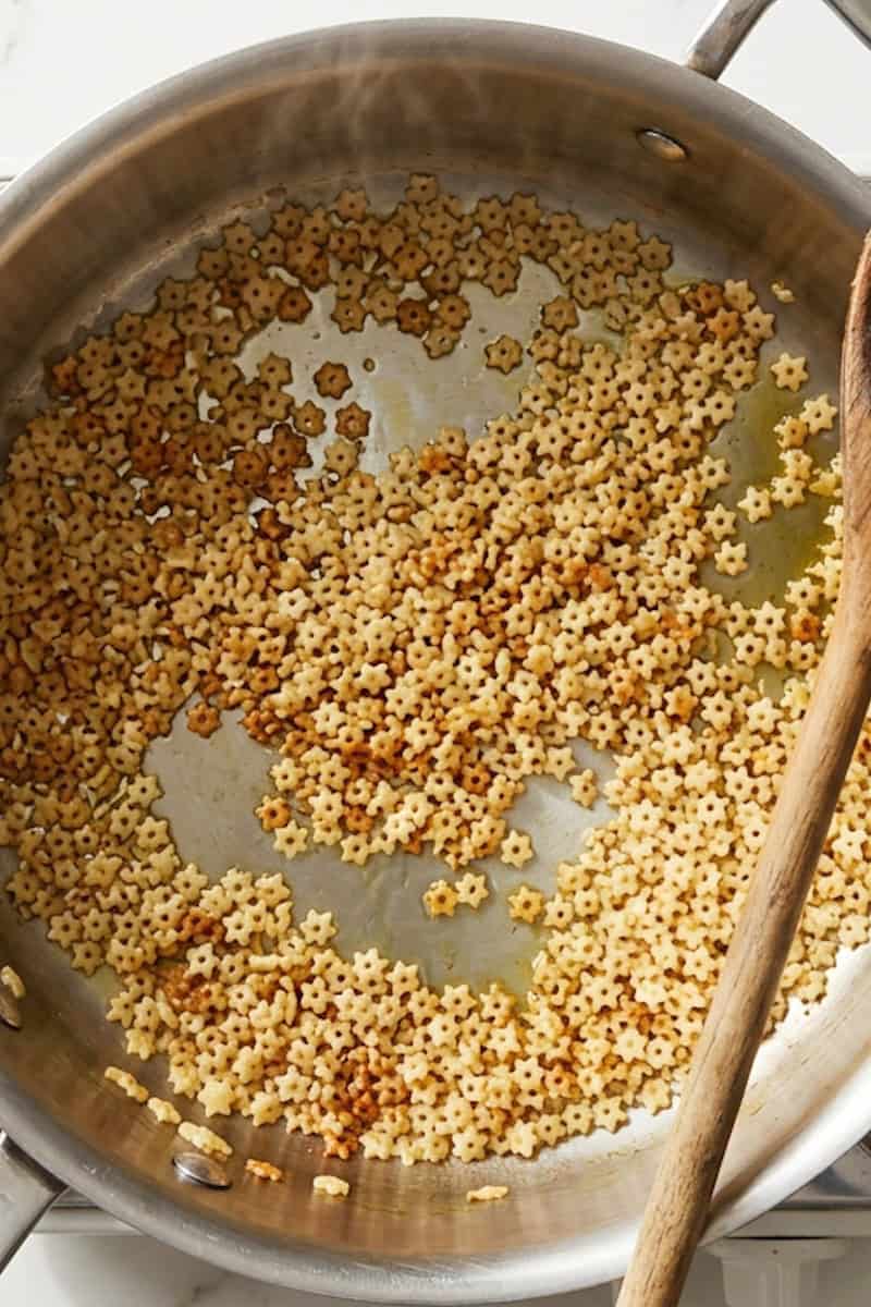 Star-shaped pasta toasting in olive oil until golden