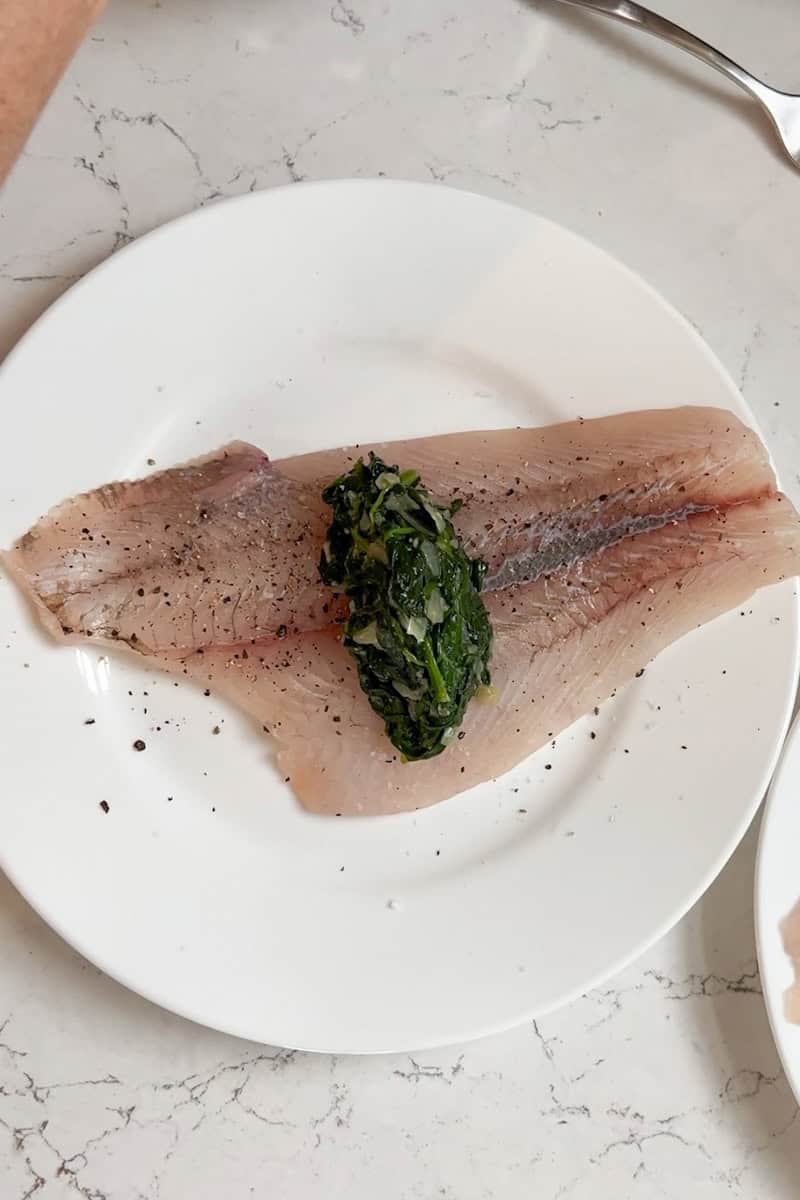 Flounder fillets being filled and rolled around spinach