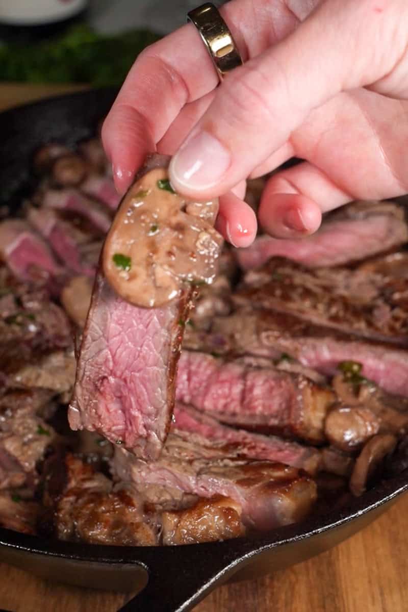 Sliced New York strip steak topped with creamy mushroom sauce and parsley