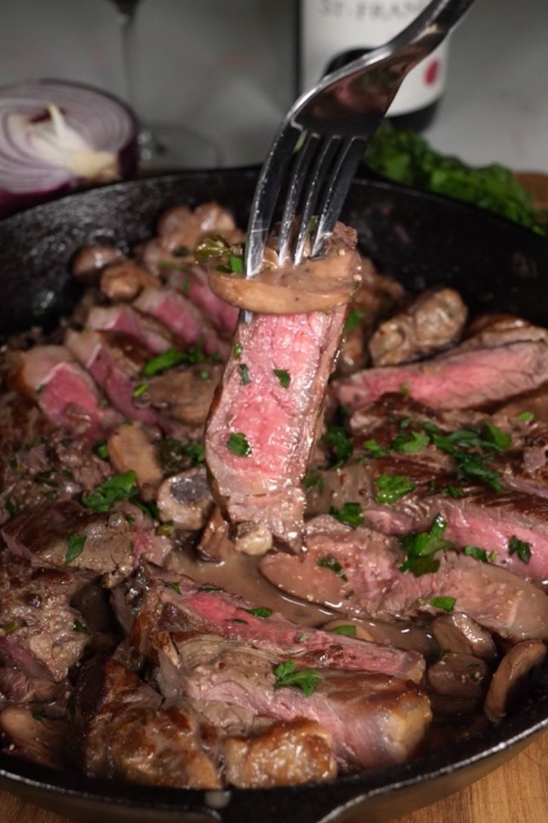 Sliced New York strip steak topped with creamy mushroom sauce and parsley