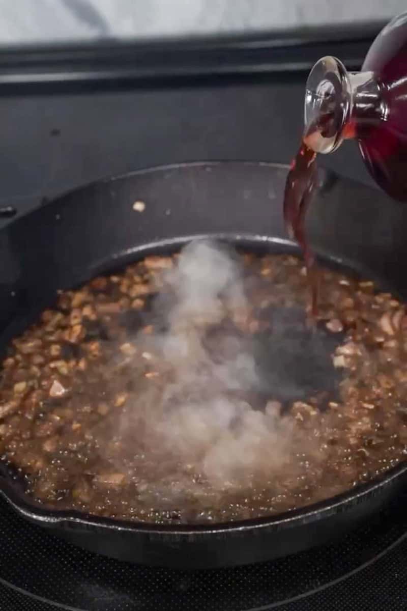 Shallot and vermouth pan sauce simmering in a cast-iron skillet