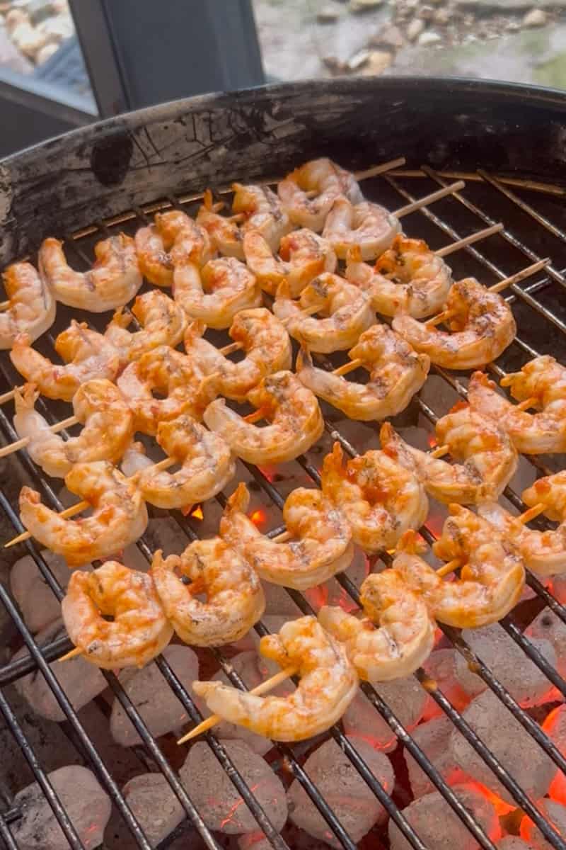 Shrimp skewers cooking over high heat on an outdoor grill