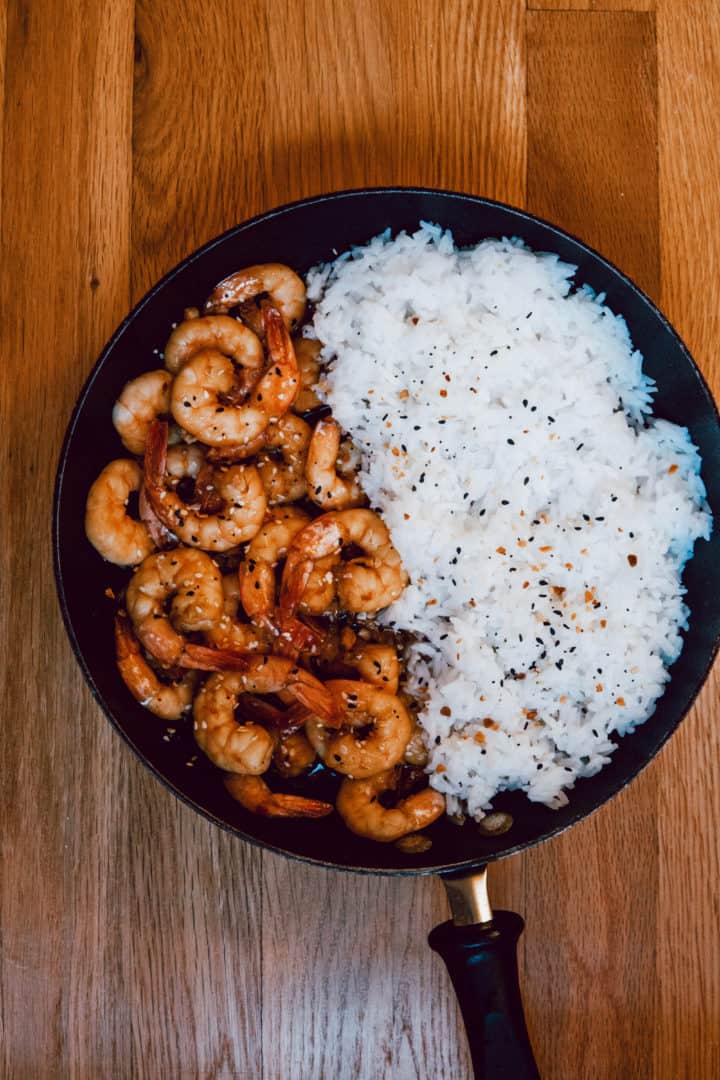 Serve the sticky garlic honey shrimp over cooked rice. Garnish with sesame seeds and chopped scallions.