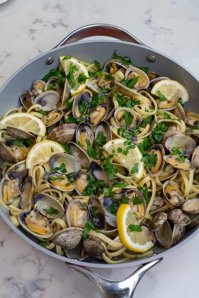 Este Espaguetis con Almejas está hecho con almejas, mantequilla, hojuelas de pimiento rojo, ajo, vino blanco, limones y perejil.