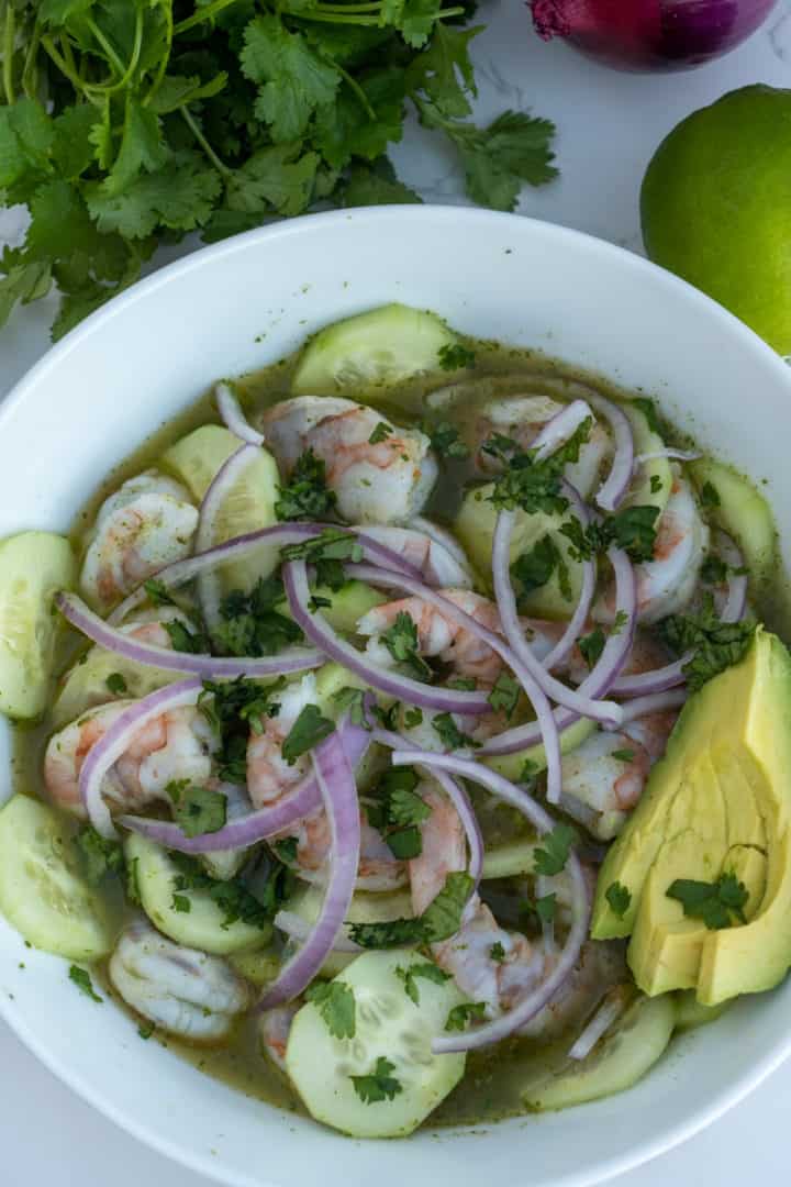 Take the bowl out of the refrigerator and assort the cucumber between the shrimp. Top with red onions and add the avocado on the side. Enjoy this Shrimp Aguachile Recipe (Aguachile de Camarón).