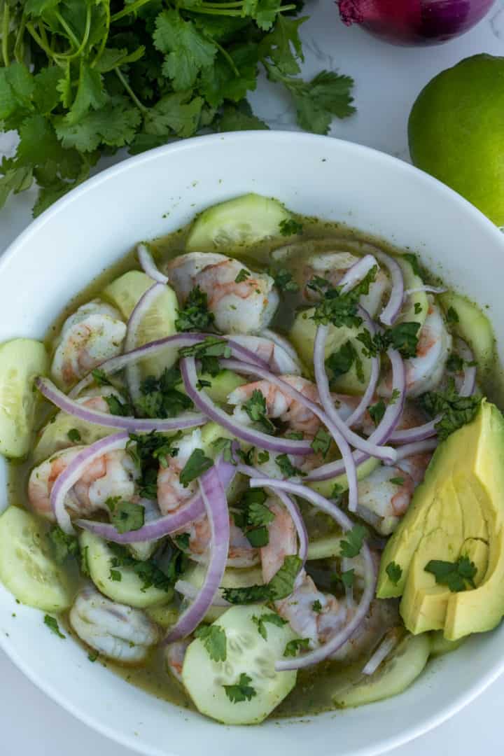 Take the bowl out of the refrigerator and assort the cucumber between the shrimp. Top with red onions and add the avocado on the side. Enjoy this Shrimp Aguachile Recipe (Aguachile de Camarón). 