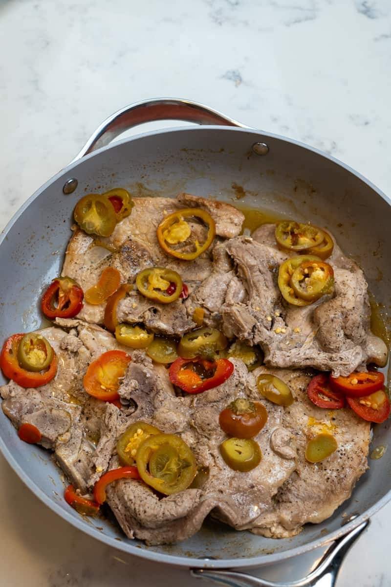 Repeat on the other side. Lower the heat to medium low, throw in the hot and sweet cherry peppers along with the juice and cover for twenty minutes, until chops are done. 