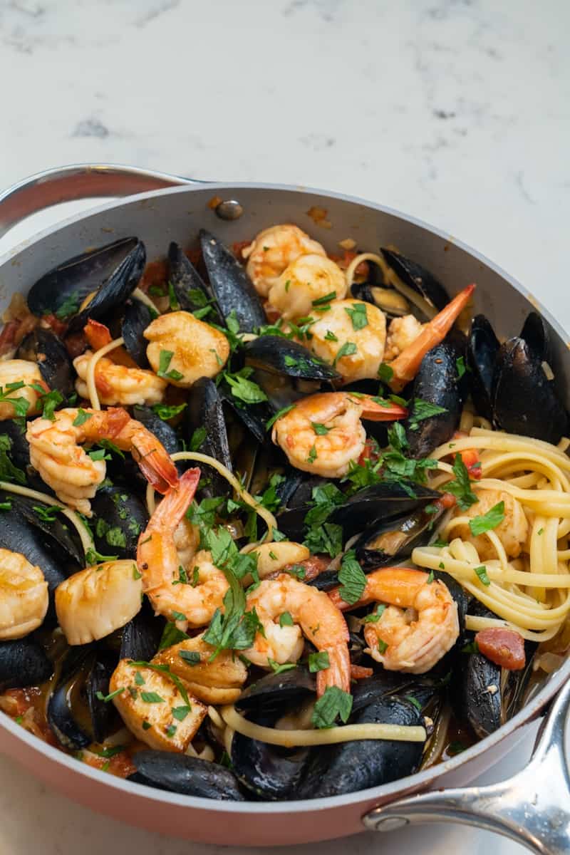 Agrega el linguini o spaghetti. Agregue las vieiras nuevamente. Decorar con perejil. Disfrute esta Pasta con Mariscos (Mejillones, Vieiras y Camarones).