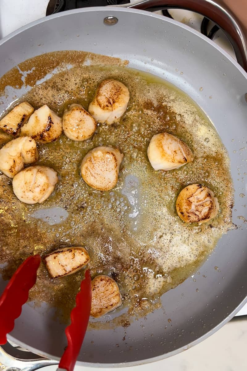 Place 1 tablespoon of olive oil into a large deep pan on medium high and place scallops into it. Sear only 2-3 minutes on each side. 