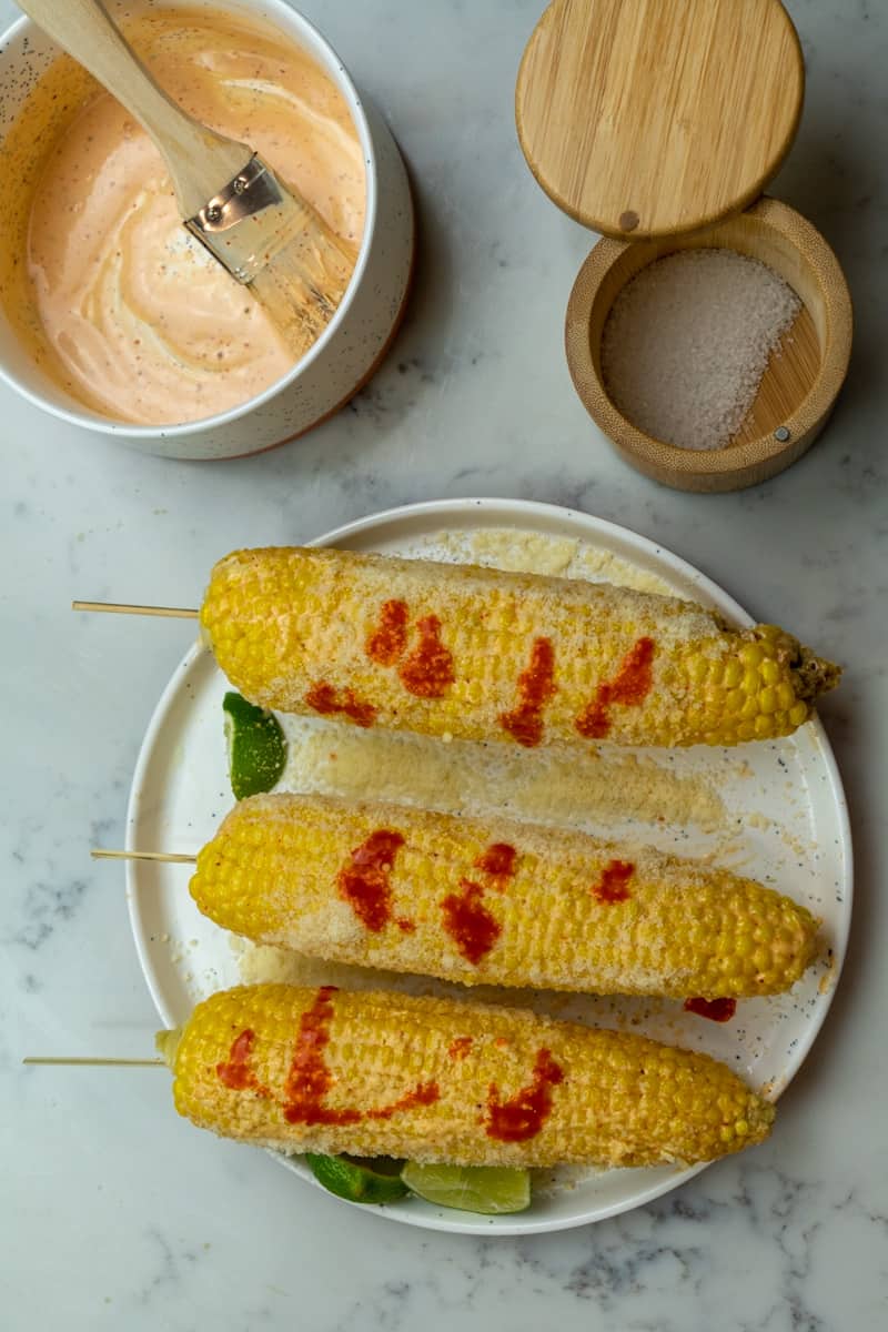 This Mexican Corn Recipe (Elote Mexicano) is made with corn, mayonnaise, chili powder, hot sauce, lime juice, and topped with cotija cheese.
