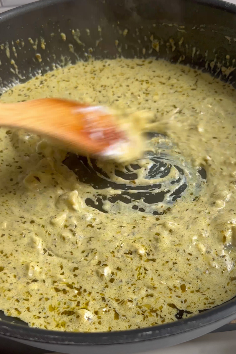 Baje el fuego y agregue el queso de cabra y el pesto, revolviendo rápidamente. Agregue lentamente aproximadamente ½ taza de agua de pasta y siga revolviendo hasta que el queso de cabra se derrita por completo.