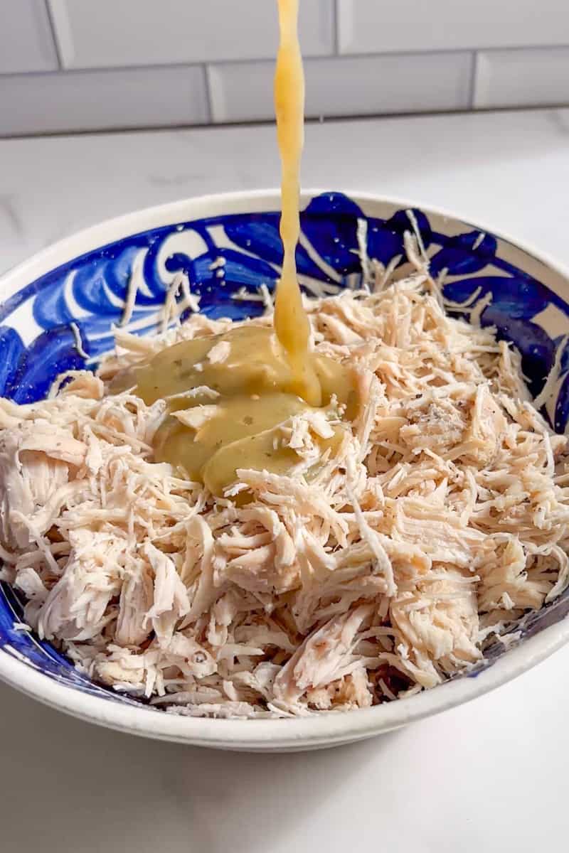 Add the shredded chicken in a bowl and pour 1 cup of enchilada sauce into the chicken. Mix well. Heat up the tortillas by wrapping them in a damp towel and microwaving for about 45 seconds. This will prevent them from cracking when rolling up. 