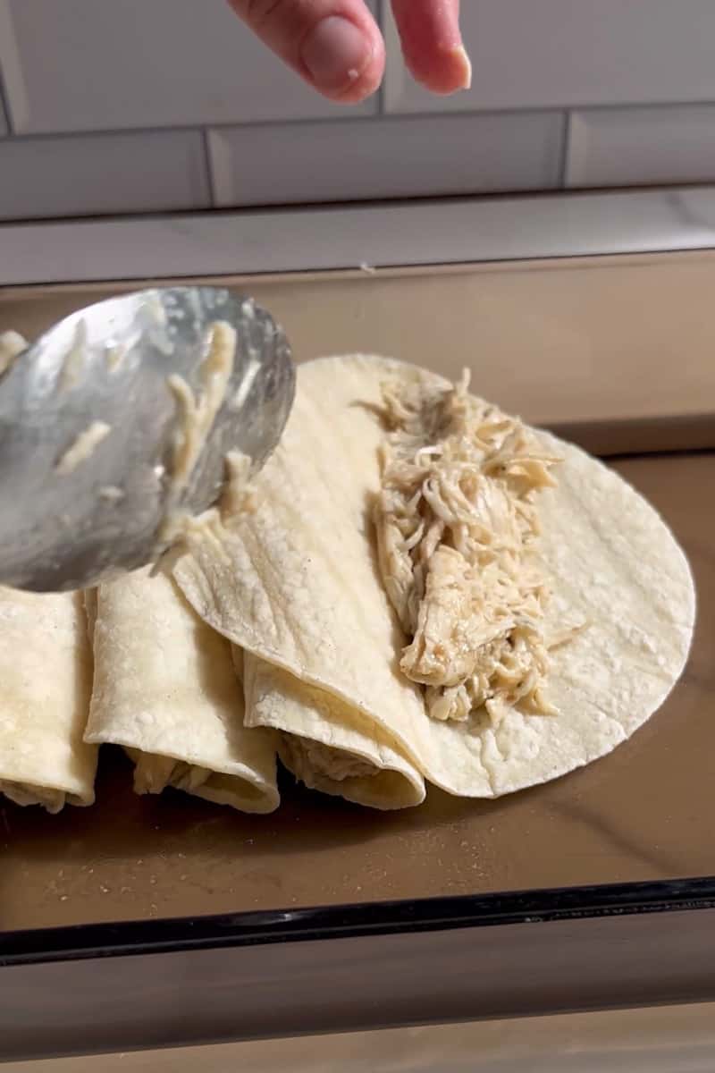 Add the sour cream, garlic powder, and milk in a bowl and stir until a thin sauce. Add more milk if needed. Lay out the warm tortilla and spread 2-3 tablespoons of chicken for each. Roll up the tortilla and place in a 9x13 inch baking dish. Repeat with the rest of the tortillas.