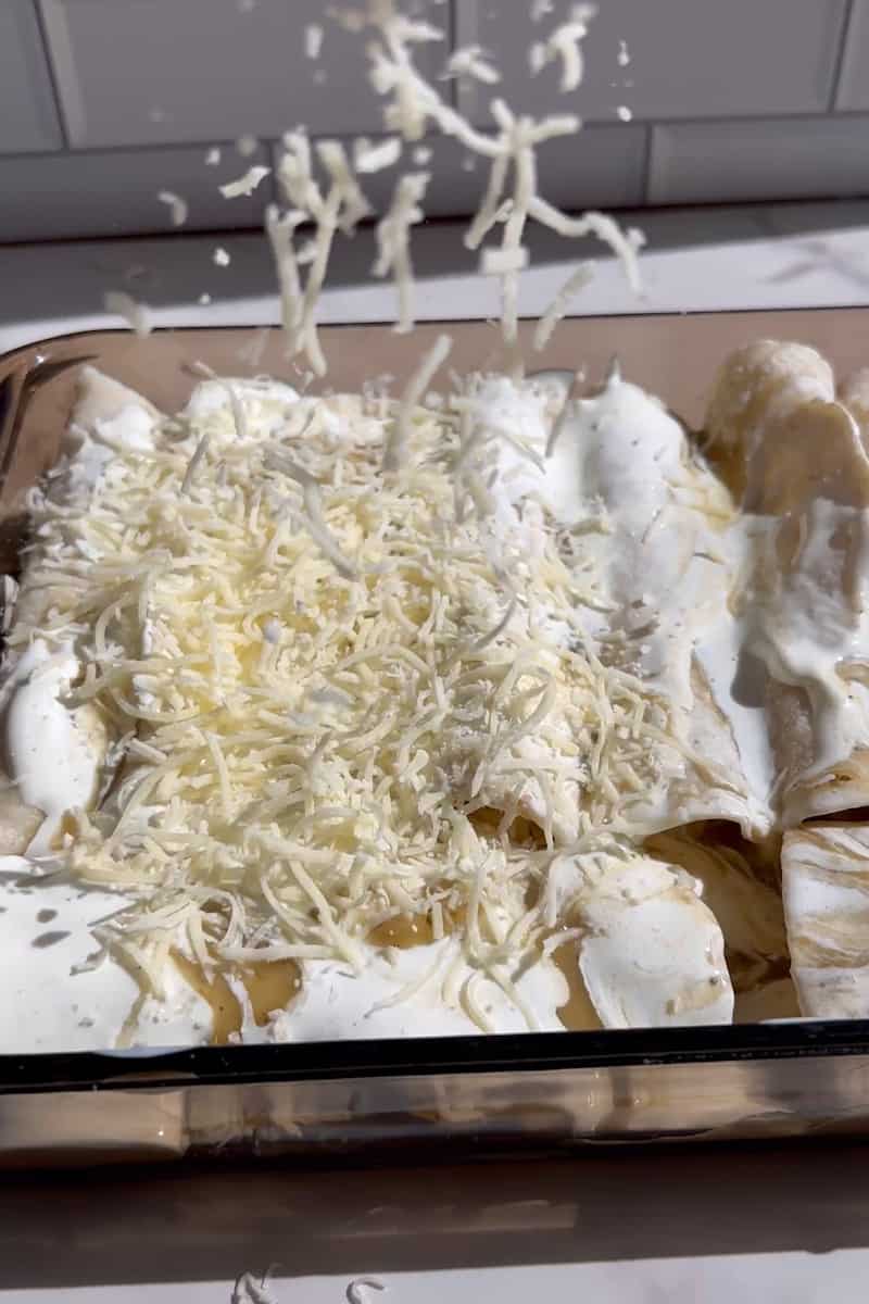 Arma las tortillas restantes y vierte el resto de la salsa sobre las enchiladas. Rocíe la salsa de crema agria encima. Espolvorear la mozzarella encima. Agregue las enchiladas, sin tapar, al horno durante 15 minutos, hasta que las tortillas estén crujientes y el queso se dore.