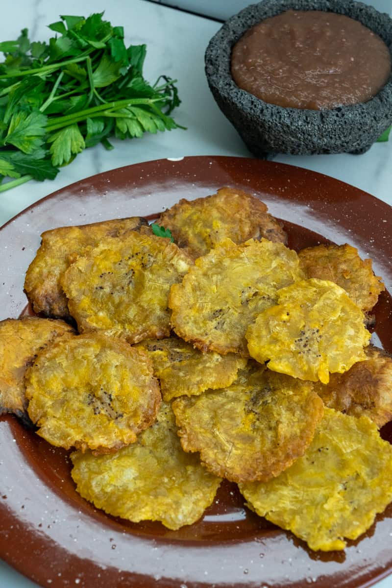 Transfiera a otro plato forrado con toallas de papel y sazone con sal marina gruesa. Disfrute estos Tostones de Platano Receta.