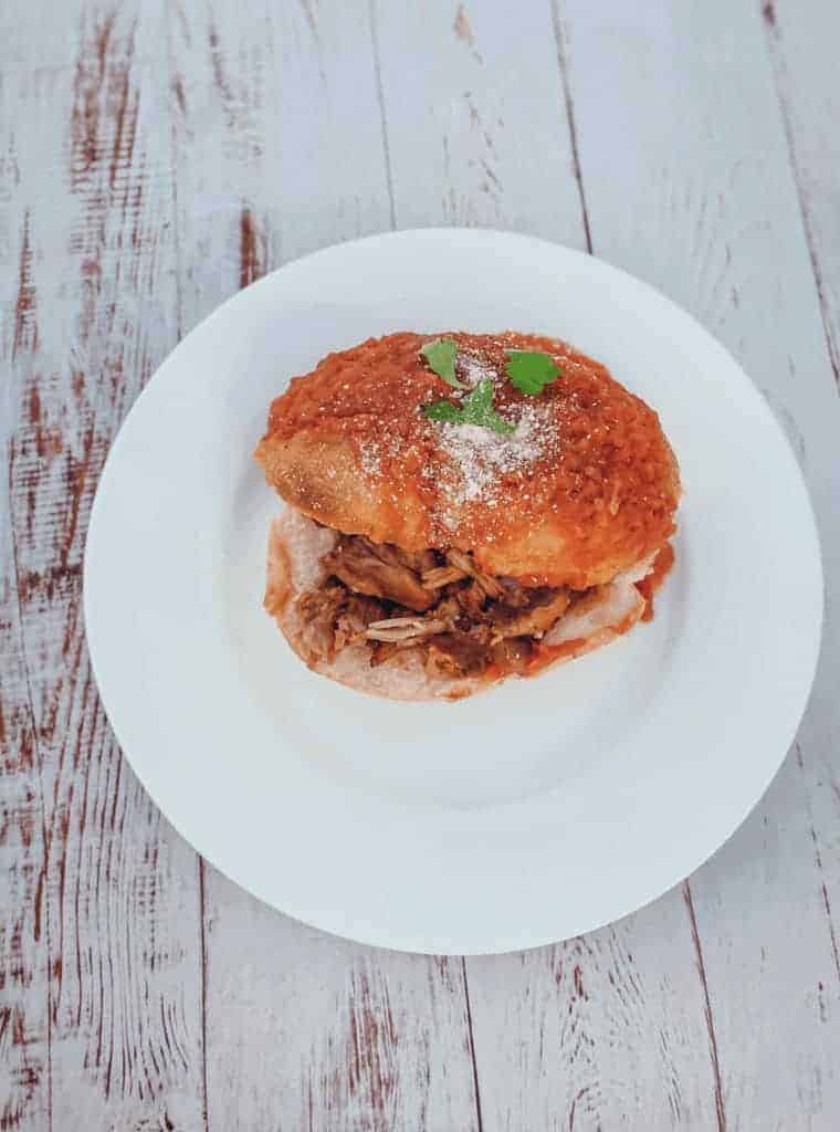 This Receta de Tortas Ahogadas dish is made with carnitas, refried beans, hot sauce, hard rolls and dipped in a tomato sauce. 