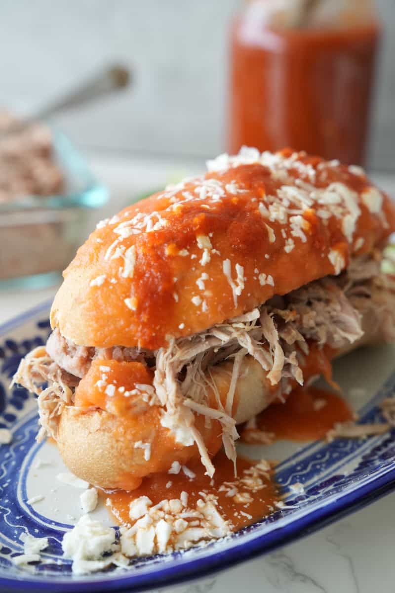 This Tortas Ahogadas Recipe is made with carnitas, refried beans, hot sauce, hard rolls and dipped in a tomato sauce. 