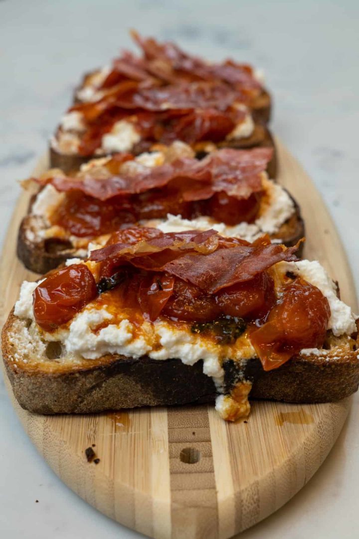 This Prosciutto and Ricotta Toast with Honey Roasted Tomatoes is made with sourdough bread or a baguette, ricotta, lemon, honey, and basil.