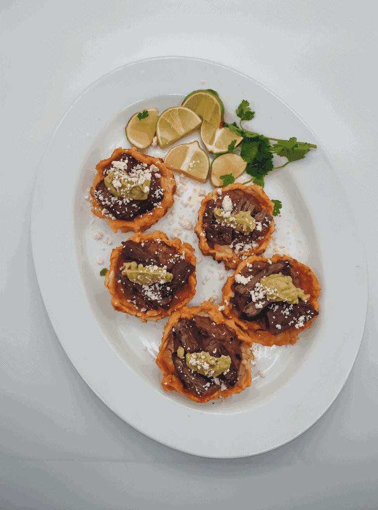 This Mexican Sopes with Carne Asada is made with carne asada, refried beans, maseca, guacamole and cotija cheese.