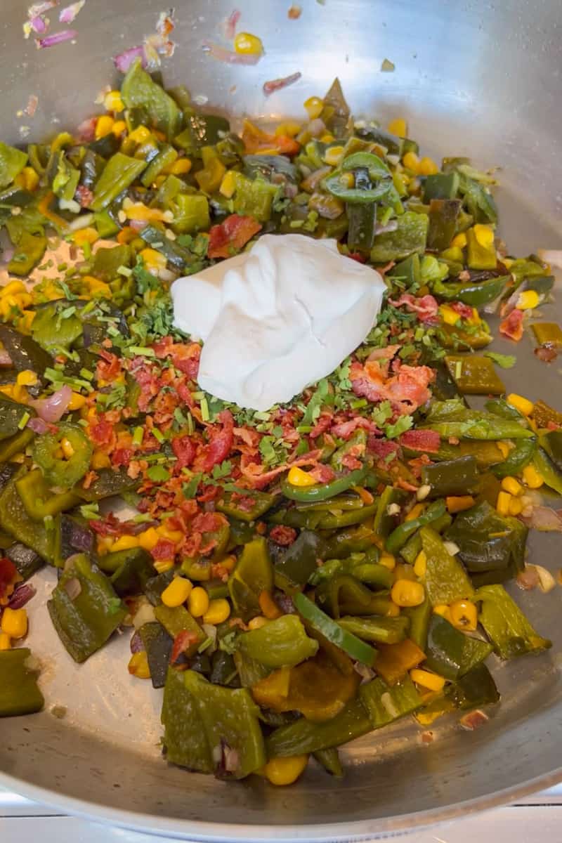 Remove from heat and add the sliced roasted poblano peppers, sour cream, bacon and cilantro. Salt generously.