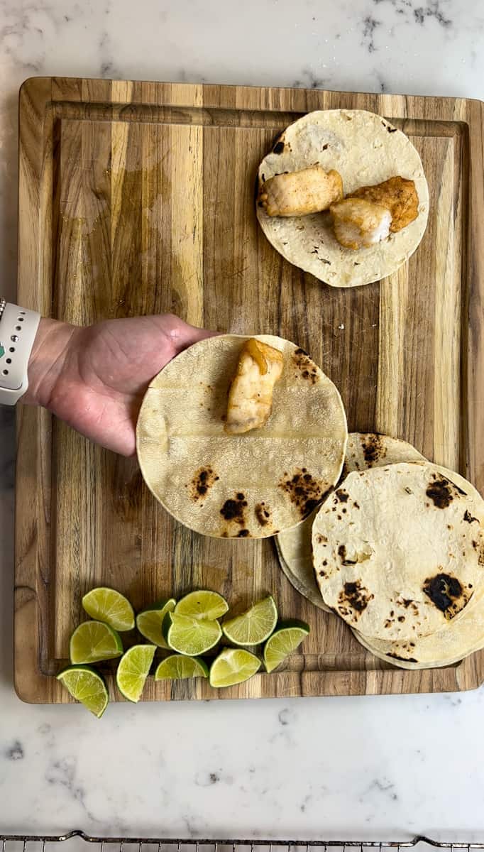 Assemble the tacos. Top each warm corn tortilla with fish. 