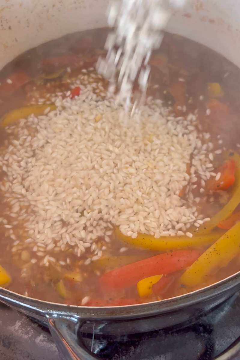 Pour in the white wine with the saffron, chicken broth and bay leaves and bring to a boil.  Reduce heat to medium low and add the rice, olives and return the chicken.