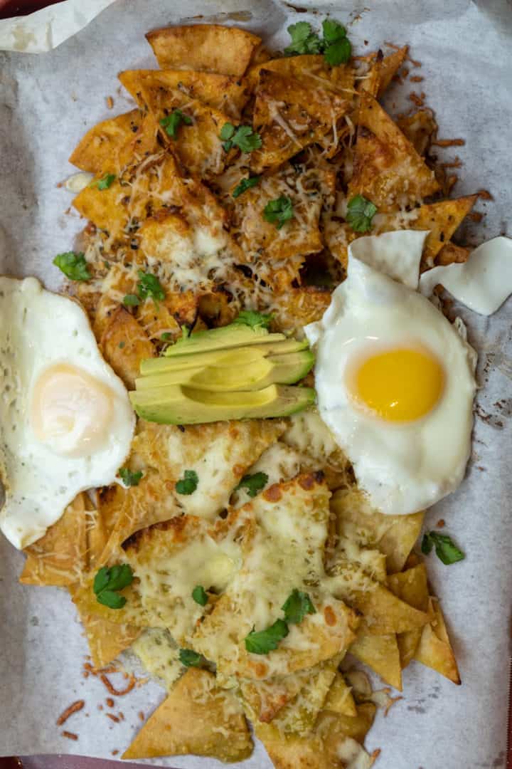 These are Chilaquiles Divorciados with eggs, avocado, cilantro, queso fresco, and Salsa Verde and Salsa Roja and baked to perfection. 