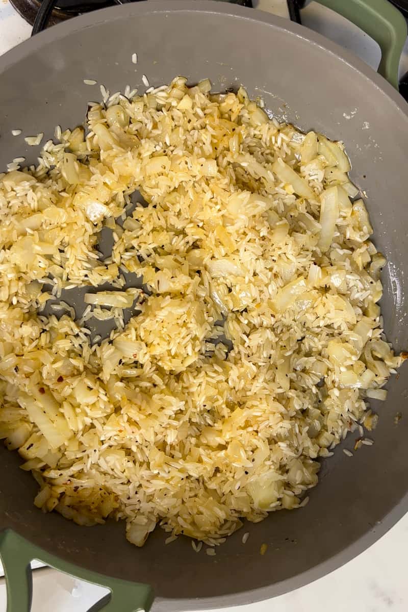 In a large pot over medium high heat, add butter and wait for it to shimmer. Add onion and garlic and cook until soft, about 3-5 minutes. Deglaze the pot by adding the white wine. Keep cooking on medium-high heat, until the wine has cooked off. Pour in the rice and chicken broth, and season with salt and pepper. 