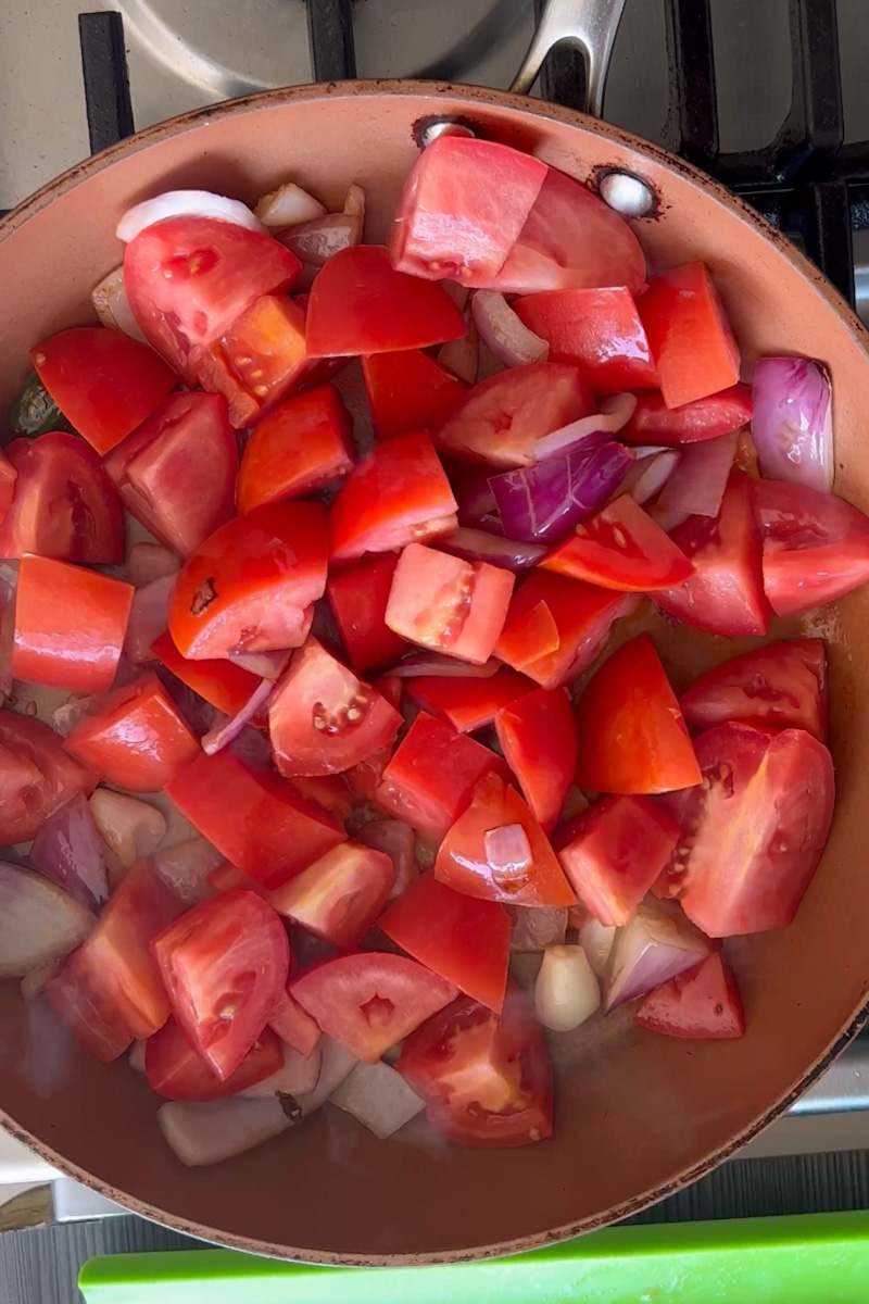 Cocine las verduras. En una sartén antiadherente grande a fuego medio, agregue aceite y espere a que este caliente. Agregue la cebolla y el chile serrano y cocine hasta que la cebolla esté suave, aproximadamente de 3 a 5 minutos. Agregue los tomates y cocine todos juntos, durante otros 6 minutos, hasta que los tomates comiencen a ablandarse. Agregue una taza de agua, cilantro, sal y pimienta y caldo de pollo, revuelva y deje hervir. Hierve durante 5 minutos.