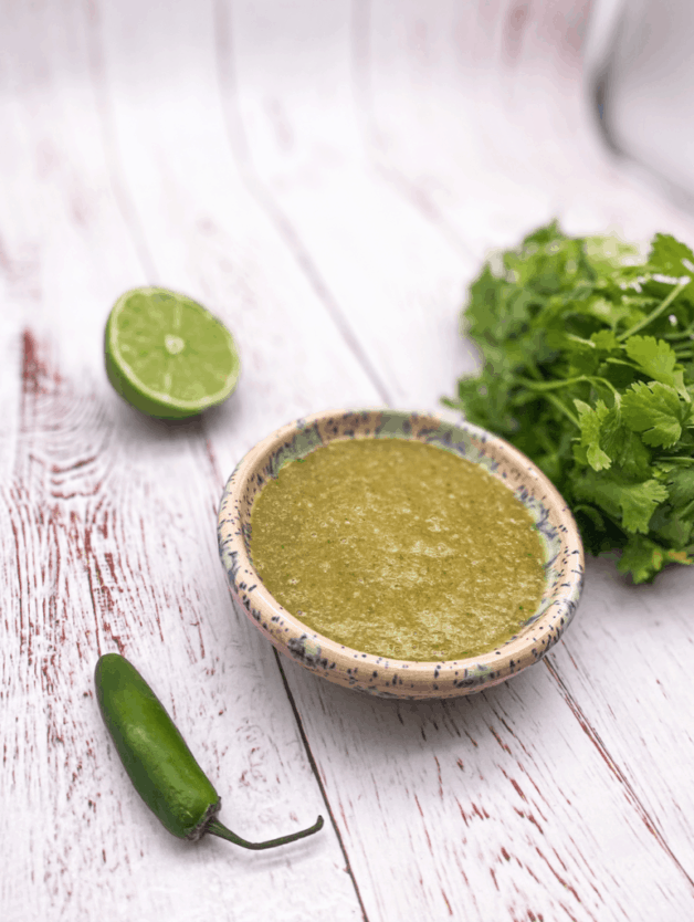 This Tomatillo Sauce Spicy is made by boiling serrano pepper, tomatillos, garlic, red onion, and blending with cilantro and lime.