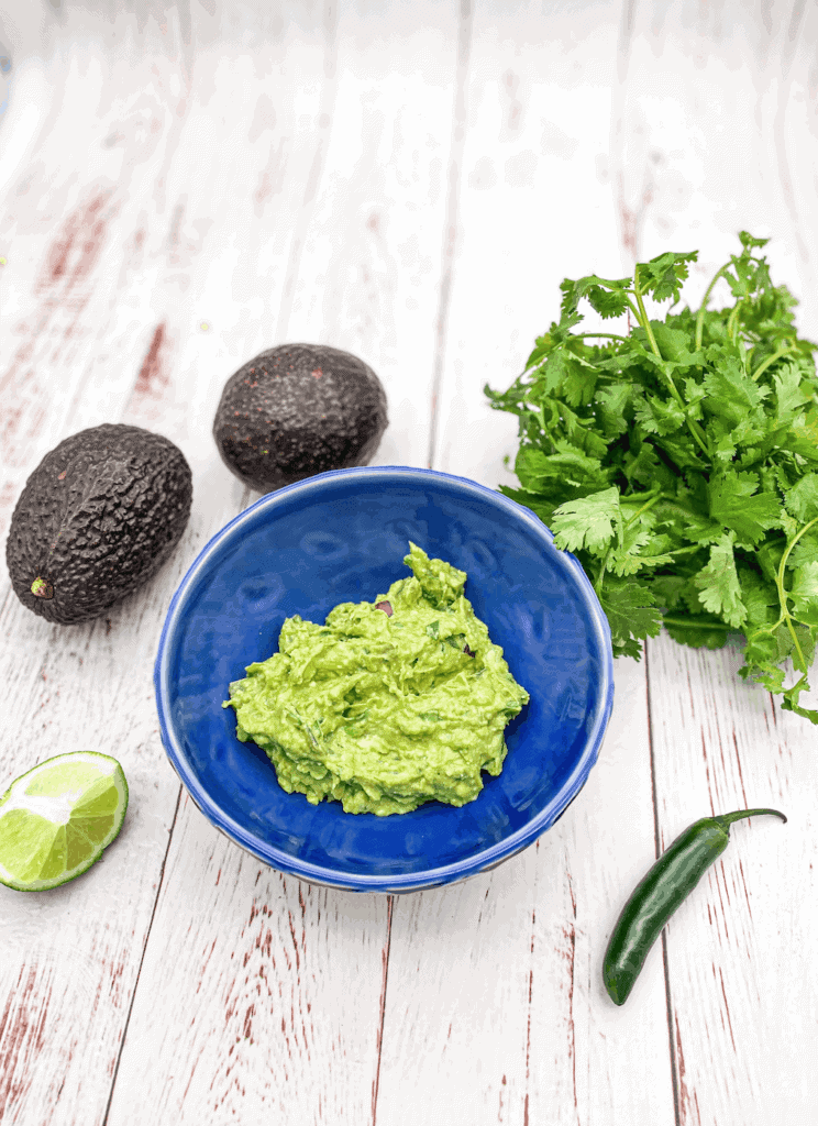 This Guacamole Recipe is made with avocado, lime, red onion, cilantro, serrano peppers, and salt and mashed to perfection.