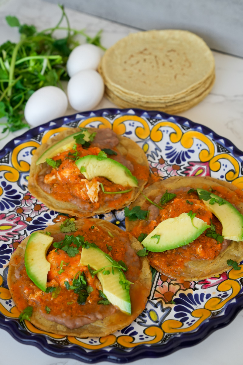 Assemble and serve. Spread the warmed refried beans on the fried tortillas. Add each fried tortillas with the poached egg on top and its some sauce. Garnish with avocado and extra cilantro. 