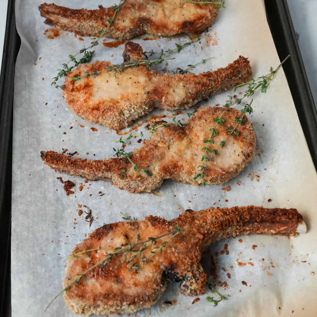 Savor the deliciousness of our Oven Baked Pork Chops Recipe: tender pork chops coated in a crispy breadcrumb crust, seasoned with fragrant thyme leaves, and baked to perfection.