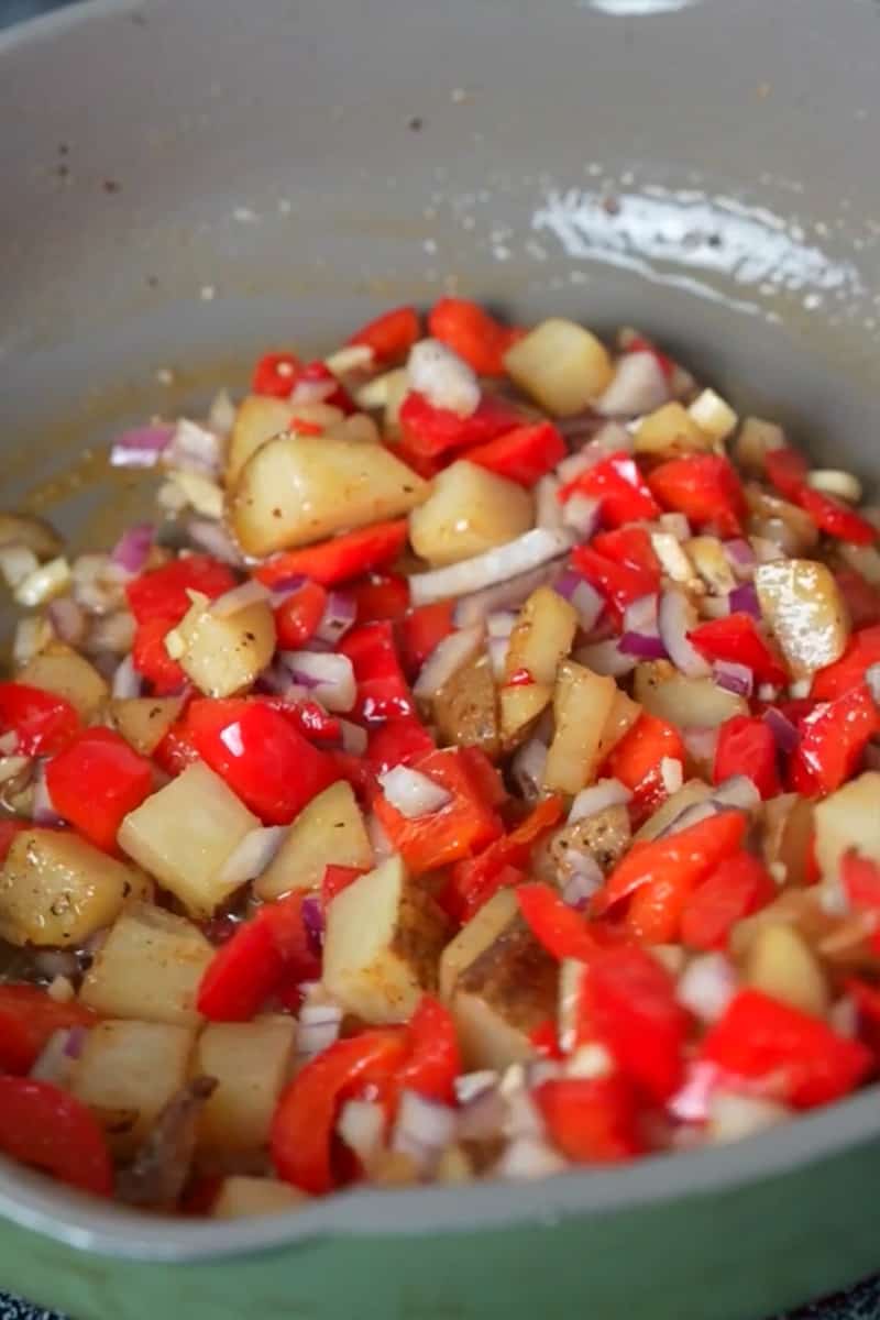 In the same skillet, add the diced onions, bell peppers, and minced garlic. Cook them until they are softened and slightly caramelized. If your potatoes are not pre-cooked or parboiled, add them to the skillet and cook until they are tender and golden brown. If you're using pre-cooked or parboiled potatoes, you can add them later with the bacon and chorizo. Once the potatoes are cooked, add the cooked chorizo and bacon back to the skillet and mix everything together.