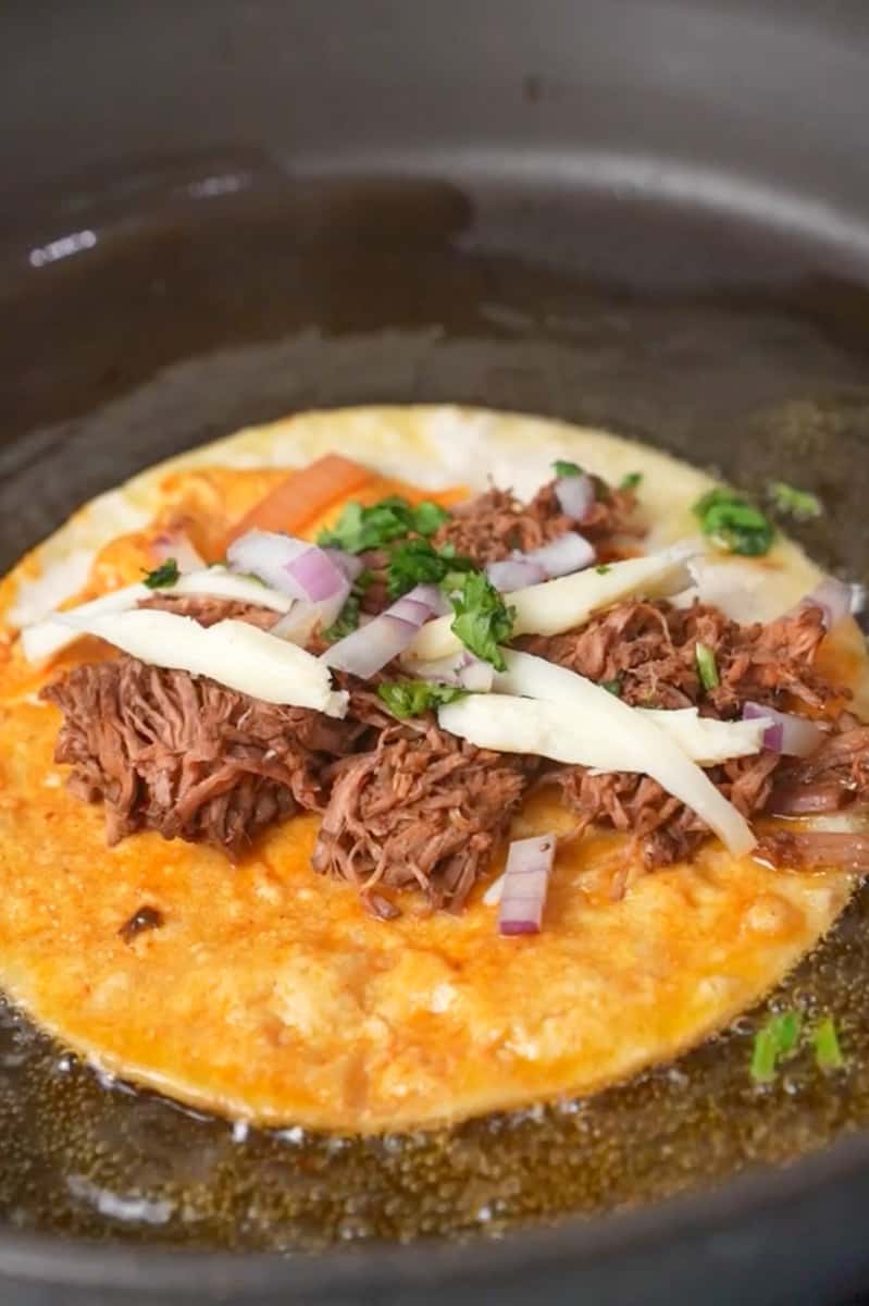 Shred the Meat: Once the meat is tender, remove it from the pot and shred it using two forks. Serve: Warm the corn tortillas. Dip the tortillas in the consomé broth, allowing them to soak up some of the rich flavors. 