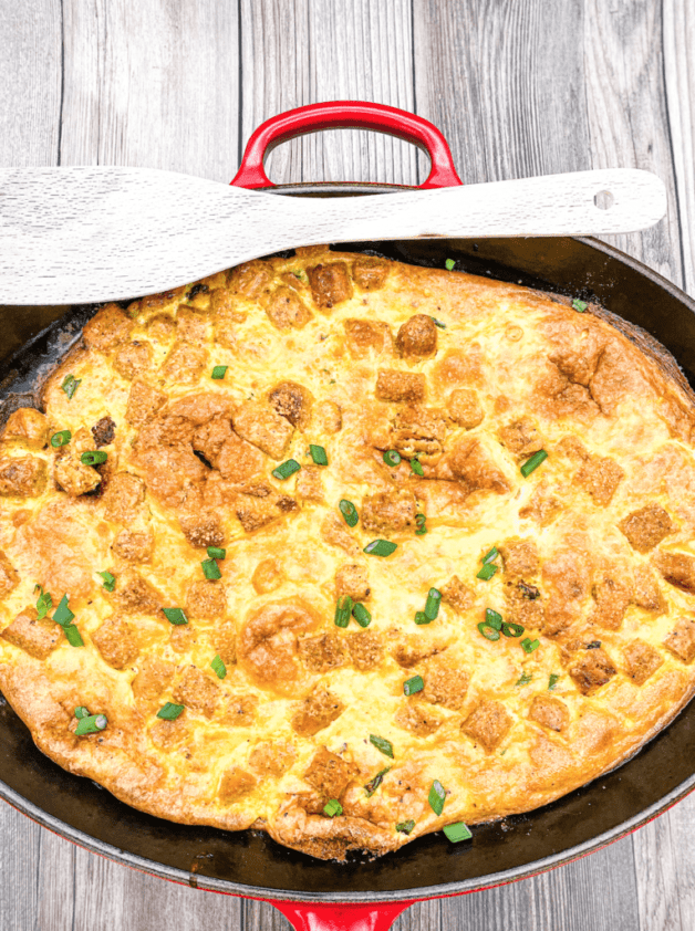 This is a Chorizo Breakfast Skillet with eggs, cream, cheese, chorizo and are cooked in a cast iron skillet and garnished with scallions. 