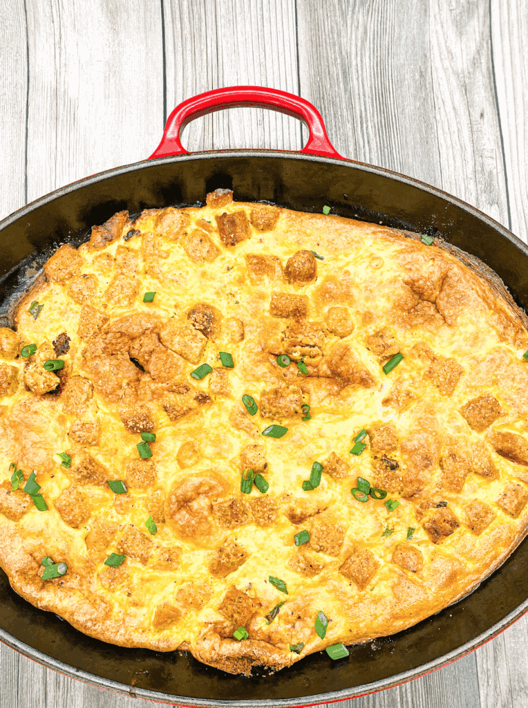 This is a Chorizo Breakfast Skillet with eggs, cream, cheese, chorizo and are cooked in a cast iron skillet and garnished with scallions. 
