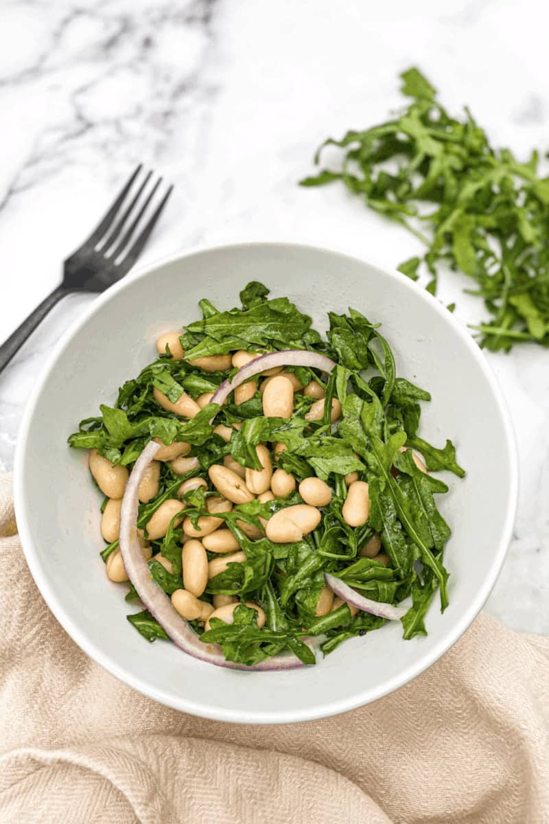 This White Bean Salad Recipe is made with arugula, cannellini beans, red onion, lemons, olive oil, maple syrup and tossed.
