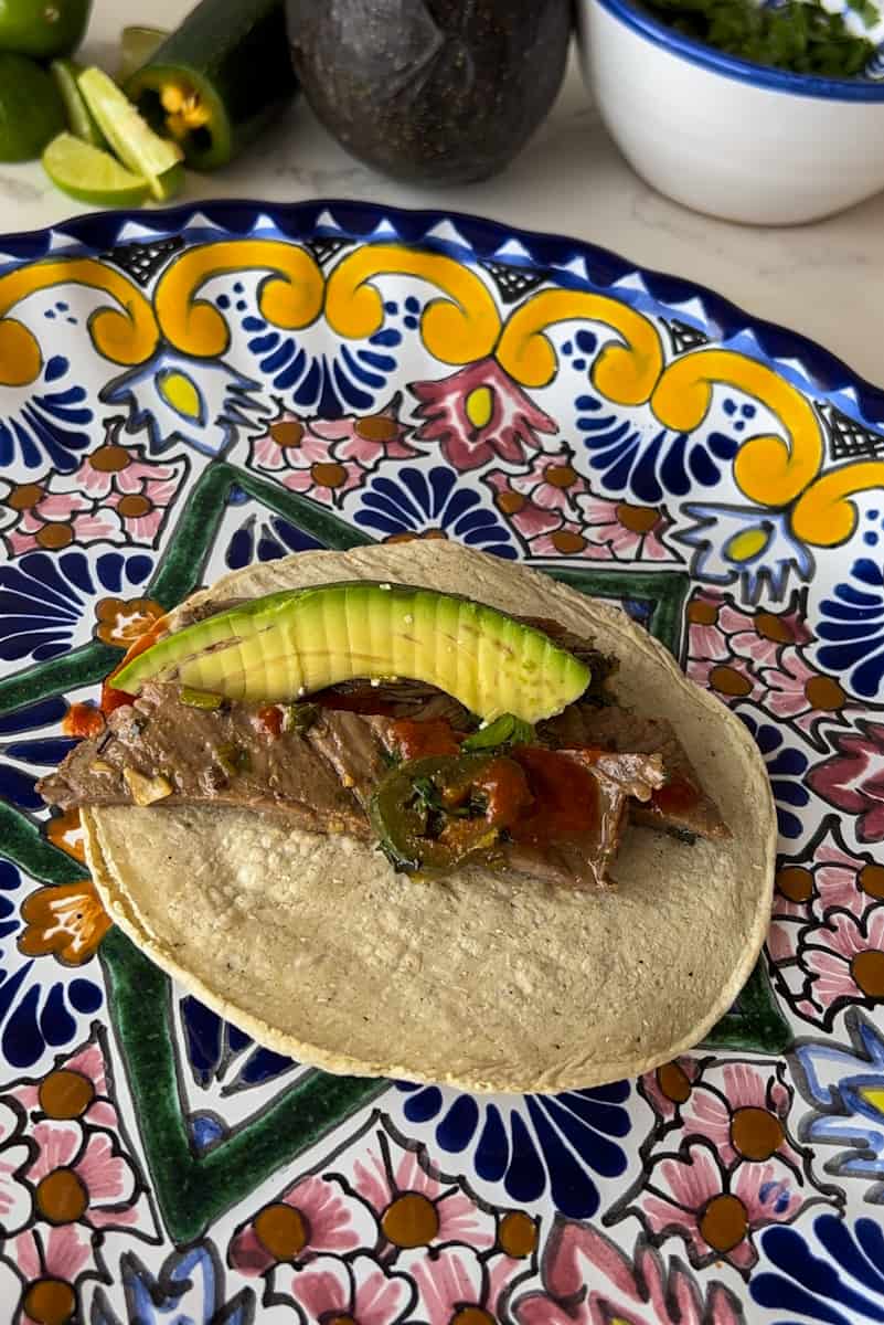 Add the cut up carne asada, top with salsa, and avocado slices.