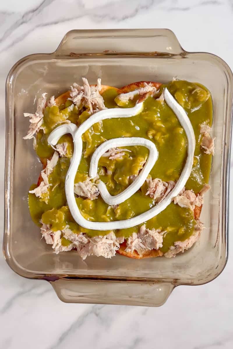 Like a lasagna, fill the baking dish with the carnitas, then half of the peppers, then half of the sour cream. Sprinkle with shredded cheese generously.
