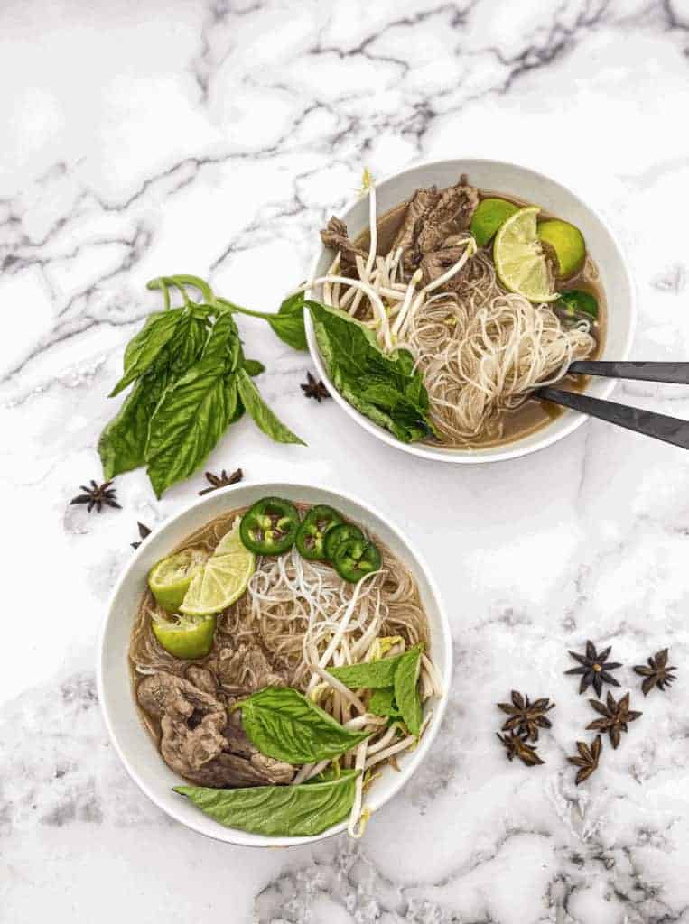 This is an easy Vietnamese Pho Tai recipe that is made with thin-cut sirloin, rice noodles and garnished with lime, cilantro, and chilies.