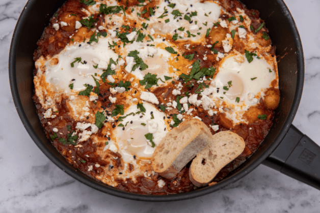 This Spicy Potato Shakshuka is made with spiced tomato sauce, harissa, poached eggs and garnished with cilantro and feta cheese!