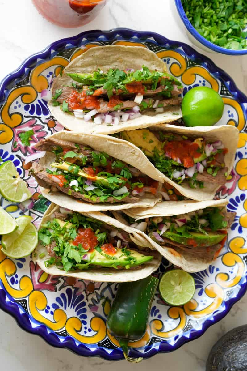 These Carne Asada Tacos Recipe is made with marinated skirt of flank or skirt steak, served on a tortilla and topped with onion and cilantro. 