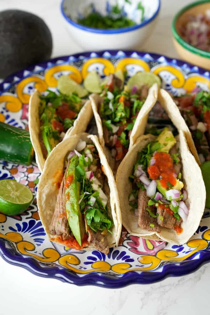 These Carne Asada Tacos Recipe is made with marinated skirt of flank or skirt steak, served on a tortilla and topped with onion and cilantro. 