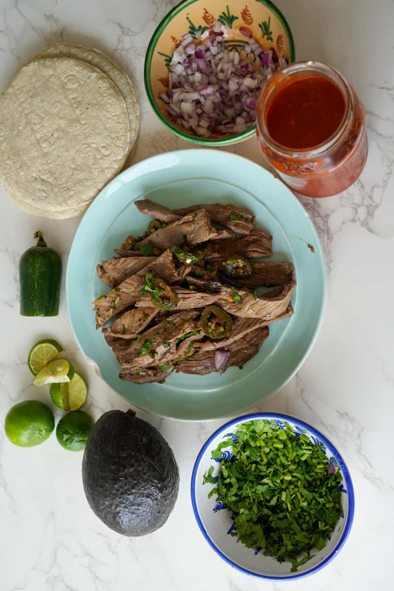 These Carne Asada Tacos Recipe is made with marinated skirt of flank or skirt steak, served on a tortilla and topped with onion and cilantro. 