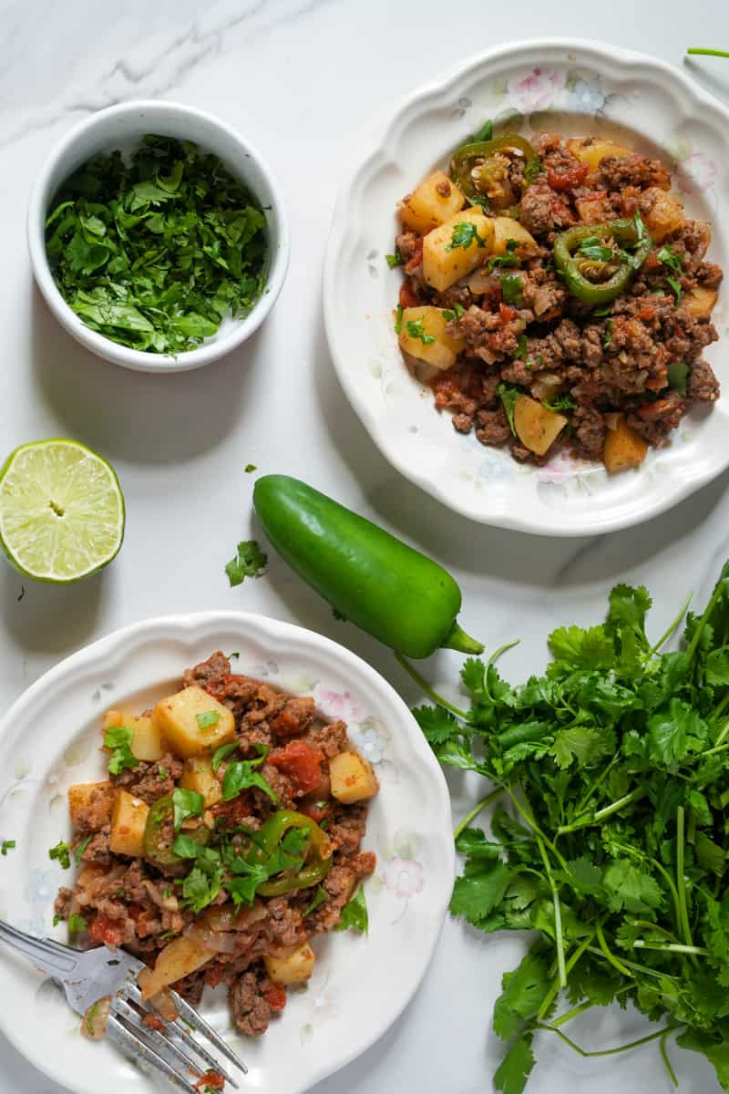 This Picadillo Recipe is made with ground beef, onion, jalapeños, chili powder, cumin, and garnished with cilantro and limes.